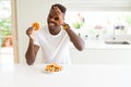 African american man eating sweet Belgian waffle with happy face smiling doing ok sign with hand on eye looking through fingers Royalty Free Stock Photo
