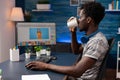 African american man editor drinking coffee while doing photo retouch