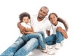 African american man embracing son and daughter while sitting together on white background Royalty Free Stock Photo