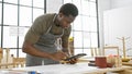 African american man focusing on a tablet while working in a bright carpentry workshop Royalty Free Stock Photo