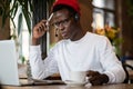 African American man in headphones sitting at cafe table taking course of E-learning, work on laptop Royalty Free Stock Photo