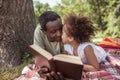 African american man and his cute kid reading a book together Royalty Free Stock Photo