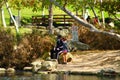 An African American man and his daughter wearing masks relaxing on the banks of the lake surrounded by lush green and autumn color Royalty Free Stock Photo