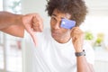 African American man holding credit card with angry face, negative sign showing dislike with thumbs down, rejection concept Royalty Free Stock Photo