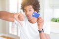 African American man holding credit card with angry face, negative sign showing dislike with thumbs down, rejection concept Royalty Free Stock Photo