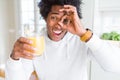 African American man holding and drinking glass of orange juice with happy face smiling doing ok sign with hand on eye looking Royalty Free Stock Photo