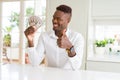 African american man holding fifty dollars bank notes happy with big smile doing ok sign, thumb up with fingers, excellent sign