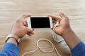 African-American man holding phone with blank screen in hands at table Royalty Free Stock Photo