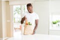 African american man holding paper bag full of fresh groceries happy with big smile doing ok sign, thumb up with fingers, Royalty Free Stock Photo