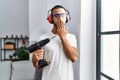 African american man holding screwdriver wearing ear protection at home covering mouth with hand, shocked and afraid for mistake Royalty Free Stock Photo