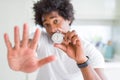 African American man holding stopwatch with open hand doing stop sign with serious and confident expression, defense gesture Royalty Free Stock Photo