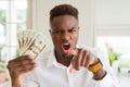 African american man holding twenty dollars bank notes pointing with finger to the camera and to you, hand sign, positive and Royalty Free Stock Photo