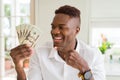 African american man holding twenty dollars bank notes very happy pointing with hand and finger Royalty Free Stock Photo