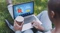 African American man with laptop browsing online cinema website in park, collage