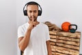 African american man listening to music using headphones at the gym asking to be quiet with finger on lips Royalty Free Stock Photo