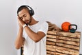 African american man listening to music using headphones at the gym sleeping tired dreaming and posing with hands together while Royalty Free Stock Photo