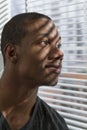 African American man looking out window and smiling, vertical Royalty Free Stock Photo