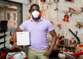 African-american man in mask with box in gardening tools shop Royalty Free Stock Photo