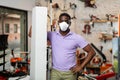 African-american man in mask with box in gardening tools shop