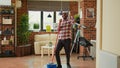 African american man mopping apartment floor to clean dust