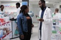 African american man pharmacist recommending woman supplements in drugstore Royalty Free Stock Photo