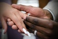 Interracial couple exchanging wedding rings at marriage ceremony