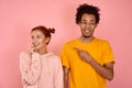 An African American man points his finger at a smiling cunning ginger woman.