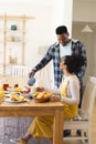 African american man pouring tea to cup at breakfast in morning at home, copy space