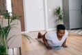 African-American man practicing burpee exercise at home, doing push-ups and jumping on yoga mat. Royalty Free Stock Photo