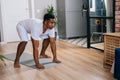 African-American man practicing burpee exercise at home, doing push-ups and jumping on yoga mat. Royalty Free Stock Photo