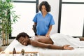 African american man reciving back massage with gun percusion at beauty center Royalty Free Stock Photo