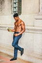 Young black man holding white rose, standing outdoors in New York City, looking down, thinking Royalty Free Stock Photo