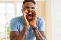 African american man shouting with rage, yelling excited with hand on mouth Royalty Free Stock Photo