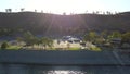 An African American man sitting on a bench on the banks of Castaic Lake surrounded by lush green trees and grass