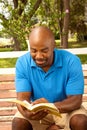 African American man sitting on a bench and reading. Royalty Free Stock Photo