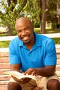 African American man sitting on a bench and reading. Royalty Free Stock Photo