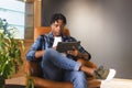 African American man sitting in chair, looking at tablet in a modern business office Royalty Free Stock Photo