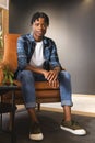 African American man sitting in chair in a modern business office, wearing casual clothes Royalty Free Stock Photo