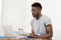 African american man sitting at home living room working with laptop computer and paperwork Royalty Free Stock Photo