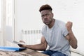 African american man sitting at home living room working with laptop computer and paperwork Royalty Free Stock Photo