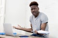 African american man sitting at home living room working with laptop computer and paperwork Royalty Free Stock Photo