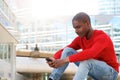 African american man sitting outside using mobile phone Royalty Free Stock Photo