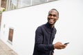 African American man smiling with mobile phone in hand while walking outside Royalty Free Stock Photo