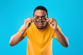 African American Man Squinting Eyes Looking Through Eyeglasses, Blue Background Royalty Free Stock Photo