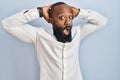 African american man standing over blue background crazy and scared with hands on head, afraid and surprised of shock with open Royalty Free Stock Photo