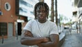 African american man standing with serious expression and arms crossed gesture at street Royalty Free Stock Photo