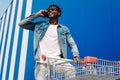 African American man talking on a cell phone and pushing a shopping cart. A black man is shopping in the city Royalty Free Stock Photo