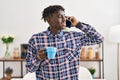 African american man talking on smartphone drinking coffee at home Royalty Free Stock Photo