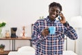 African american man talking on smartphone drinking coffee at home Royalty Free Stock Photo