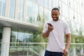 African american man talking on smartphone on street in city outdoor. Man with cell phone chatting with friends. Smiling Royalty Free Stock Photo